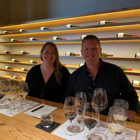 TradingGrapes founders Steph and Mitch Kerr conducting professional wine tasting in modern cellar door with premium wine display
