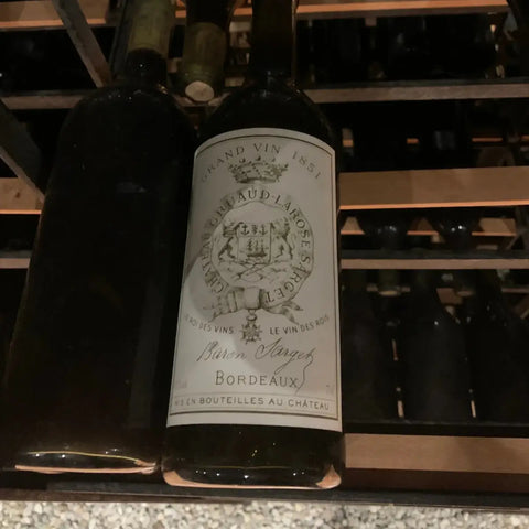 Bottle of Château Gruaud-Larose Baron Sarget Bordeaux red wine stored in a cellar wine rack, featuring its classic French label.