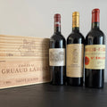 Three premium Bordeaux red wines — Lafite Rothschild 2019, Gruaud Larose 2005, and Figeac 2016 — displayed with wooden wine crates.