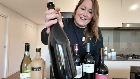 TradingGrapes co-founder Steph celebrating with premium wine collection including Lokoya and diverse wine styles in modern kitchen
